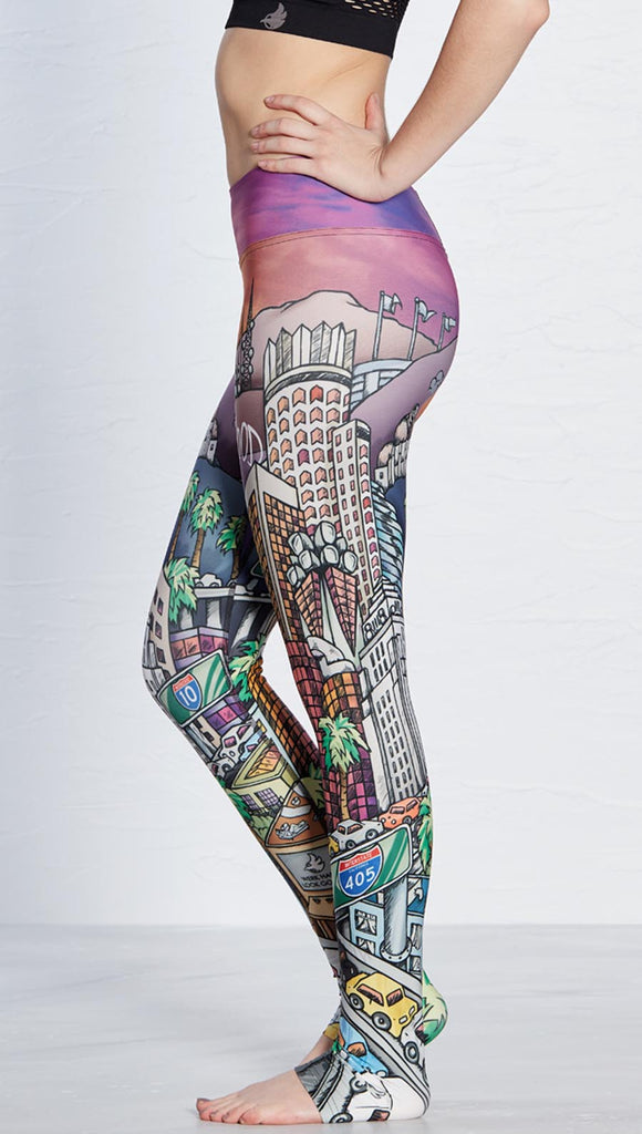 Side view of model wearing WERKSHOP Los Angeles Athleisure Leggings ~ featuring original artwork showcasing iconic LA Landmarks including the Hollywood sign, the observatory, DTLA and the 405 Freeway.