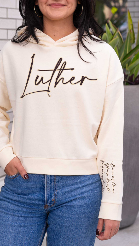 WERKSHOP  "Luther" Boyfriend Hoodie. Officially licensed from Spark of the Everflame by Penn Cole. The hoodie has "Luther" on the front chest
... and "Burn, my Queen. Glow so Bright, the darkness trembles" on the sleeve. Shown here in Bone with dark taupe writing.