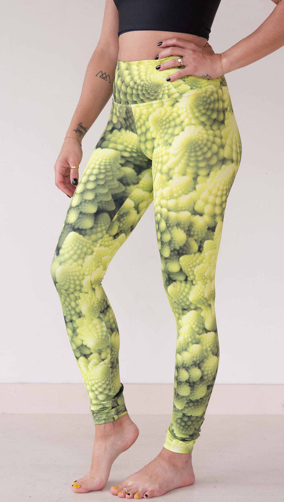 Model wearing WERKSHOP Romanesco Cauliflower Leggings. The fabric is printed with macro fractal details with bright green/yellow tones.