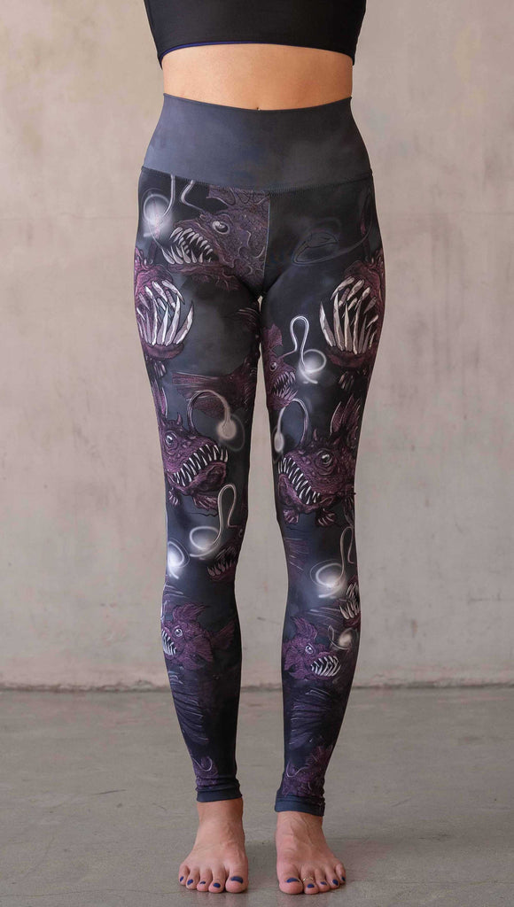 Girl wearing WERKSHOP Angler Fish Athleisure Leggings. The artwork on the leggings feature pink hued/textured angler fish over a black and gray airbrushed background