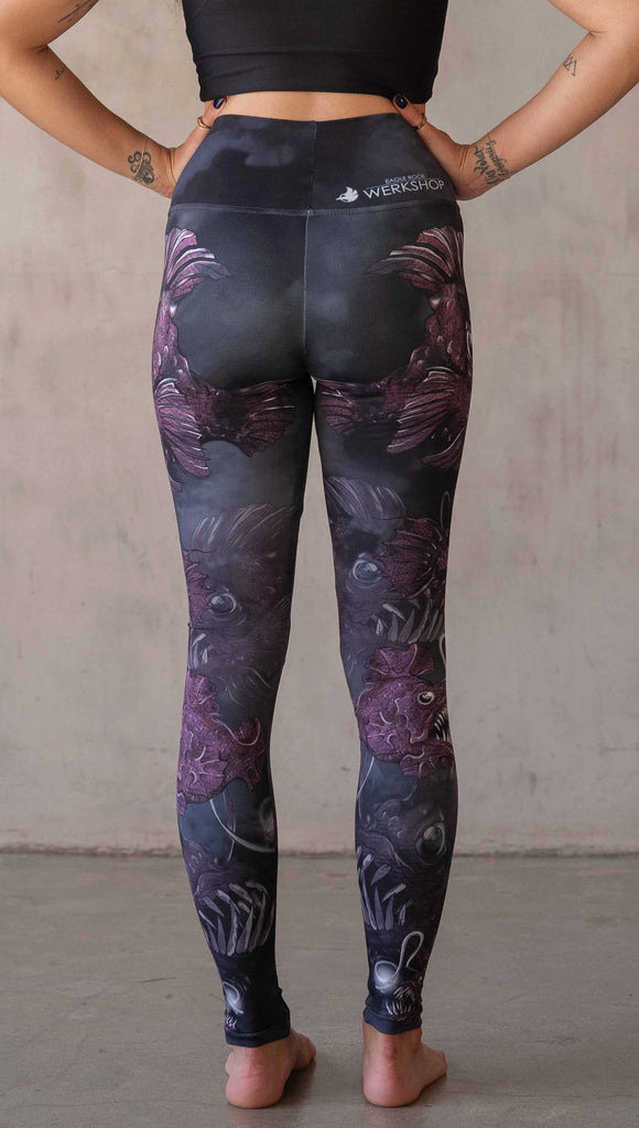 Girl wearing WERKSHOP Angler Fish Athleisure Leggings. The artwork on the leggings feature pink hued/textured angler fish over a black and gray airbrushed background