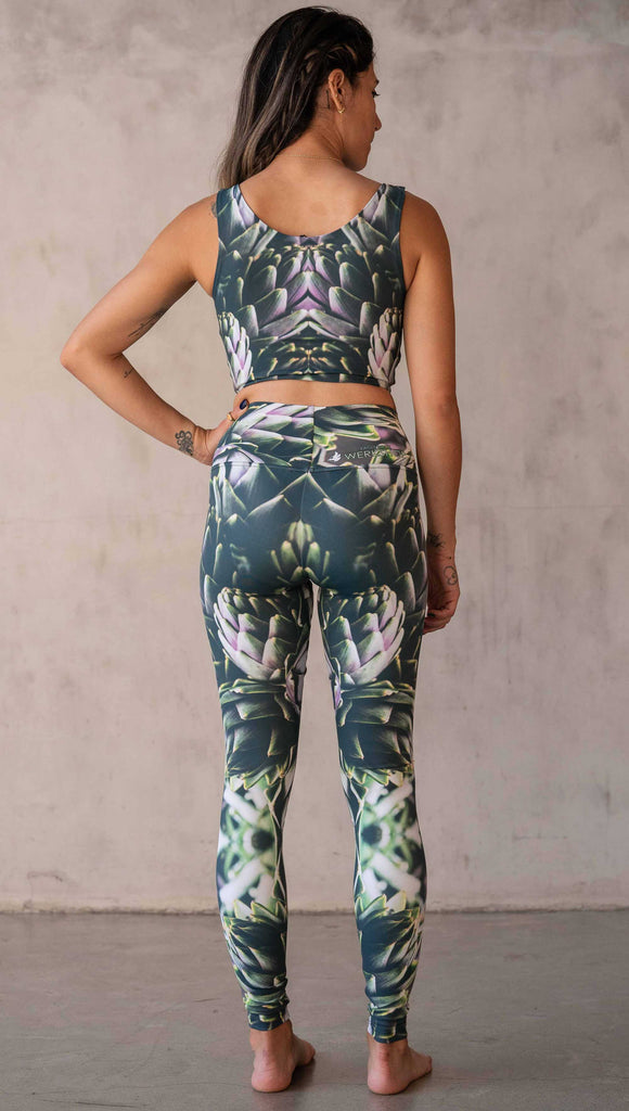 Girl wearing WERKSHOP Artichoke Athleisure Leggings. The leggings show a photo-real fractal inspired edit of artichokes. It has pops of bright green and bright purple over a mostly dark green base. It is a very geometric and fractal design.