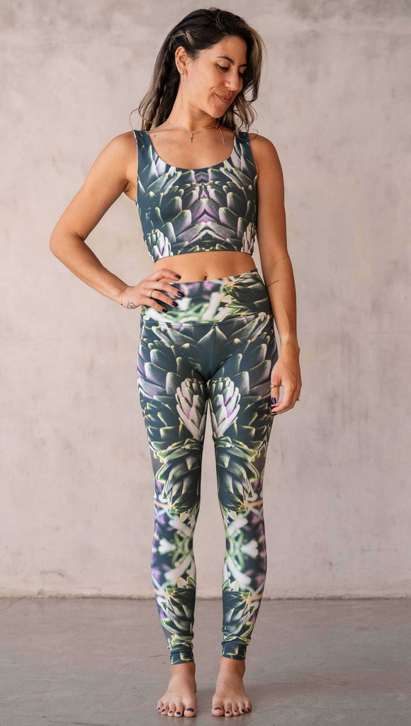 Girl wearing WERKSHOP Artichoke Athleisure Leggings. The leggings show a photo-real fractal inspired edit of artichokes. It has pops of bright green and bright purple over a mostly dark green base. It is a very geometric and fractal design.