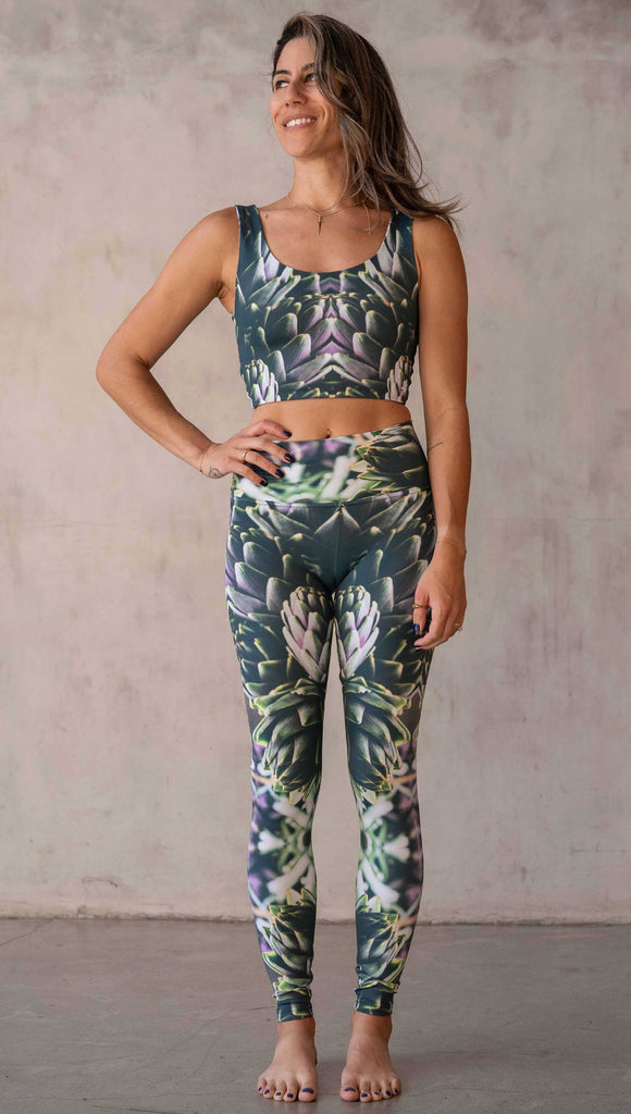 Girl wearing WERKSHOP Artichoke Athleisure Leggings. The leggings show a photo-real fractal inspired edit of artichokes. It has pops of bright green and bright purple over a mostly dark green base. It is a very geometric and fractal design.