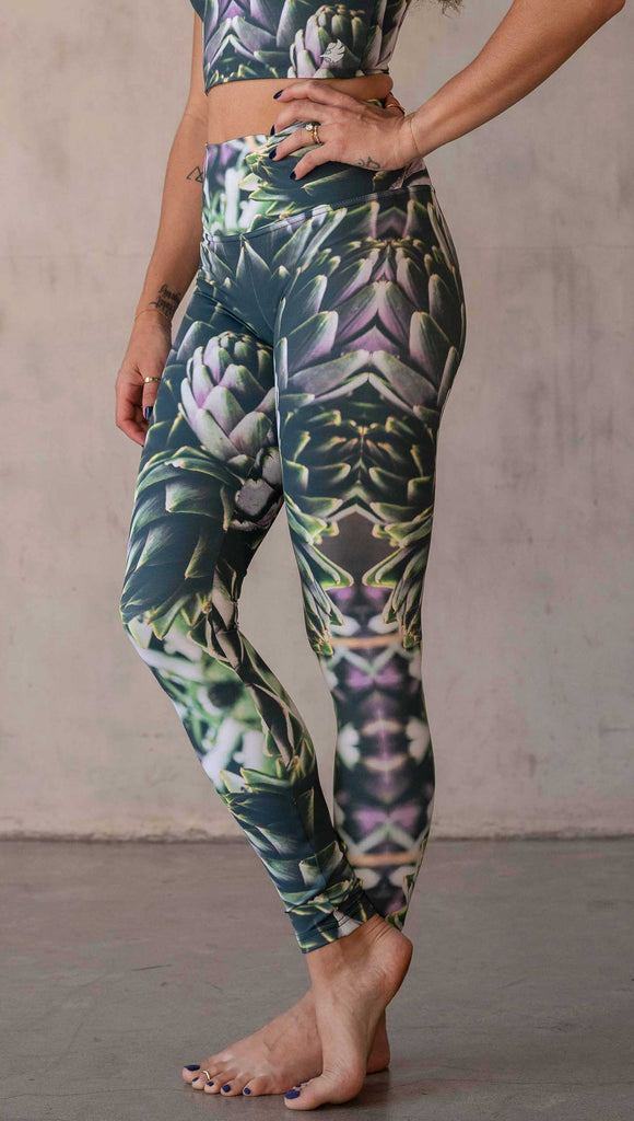 Girl wearing WERKSHOP Artichoke Athleisure Leggings. The leggings show a photo-real fractal inspired edit of artichokes. It has pops of bright green and bright purple over a mostly dark green base. It is a very geometric and fractal design.