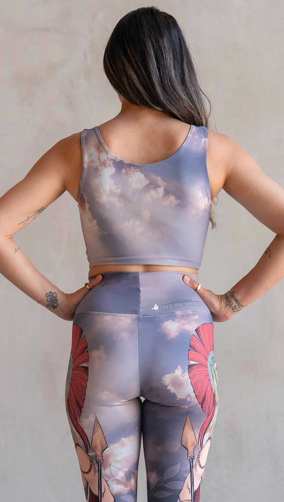 Side view of model wearing WERKSHOP Athena and Valkyrie reversible top. This top is two way reversible and each side matches either our Athena or Valkyrie leggings. The Athena side of the top features a cloudy blue sky with rays of sunlight. The Valkyrie side features an ominous taupe and warm gray stormy sky with lightening bolts