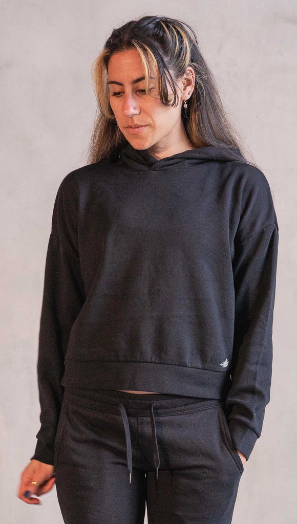 Girl wearing a Black WERKSHOP "Essential" Solid hoodie with a small eagle logo at the front bottom left corner.