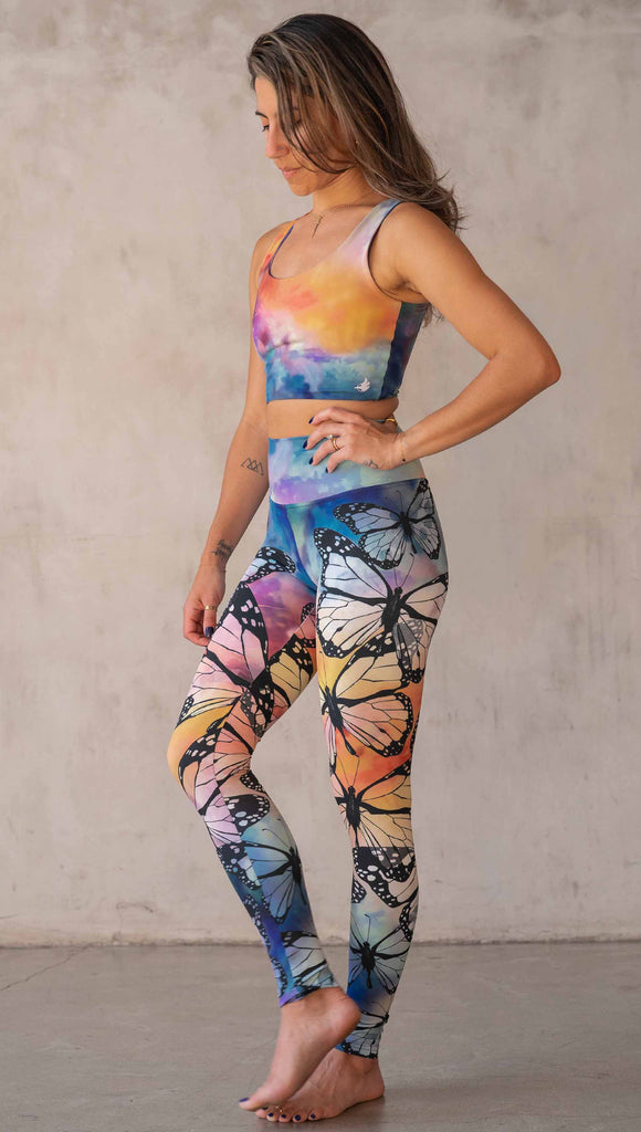 Girl wearing WERKSHOP Butterflies Athleisure Leggings. The artwork on the leggings features a black outline of monarch butterflies over a rainbow coloured watercolor background.