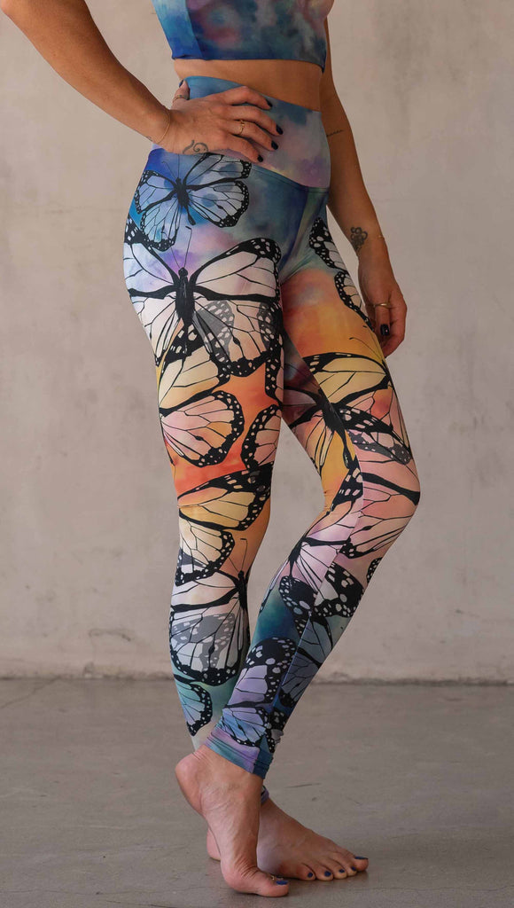 Girl wearing WERKSHOP Butterflies Athleisure Leggings. The artwork on the leggings features a black outline of monarch butterflies over a rainbow coloured watercolor background.