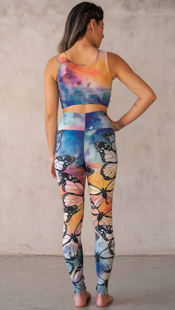 Girl wearing WERKSHOP Butterflies Athleisure Leggings. The artwork on the leggings features a black outline of monarch butterflies over a rainbow coloured watercolor background.