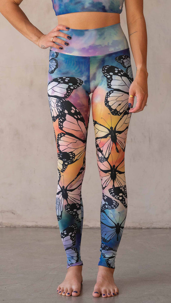 Girl wearing WERKSHOP Butterflies Athleisure Leggings. The artwork on the leggings features a black outline of monarch butterflies over a rainbow coloured watercolor background.