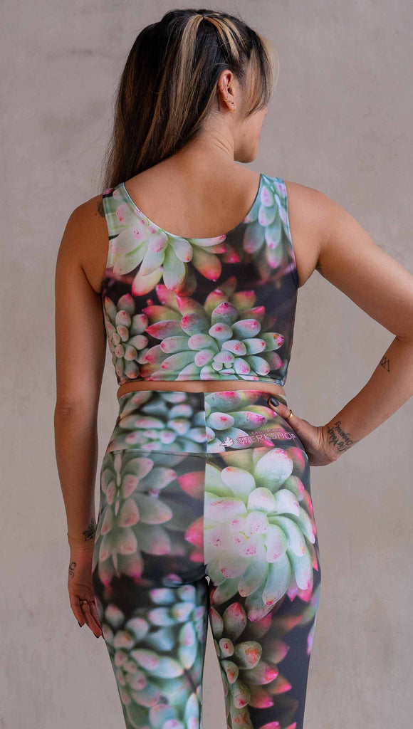 Model wearing WERKSHOP Mojave Sunset Reversible Top. One side is all green and the other side is green with bright pops of hot pink. Both sides are printed with photo-real succulents.