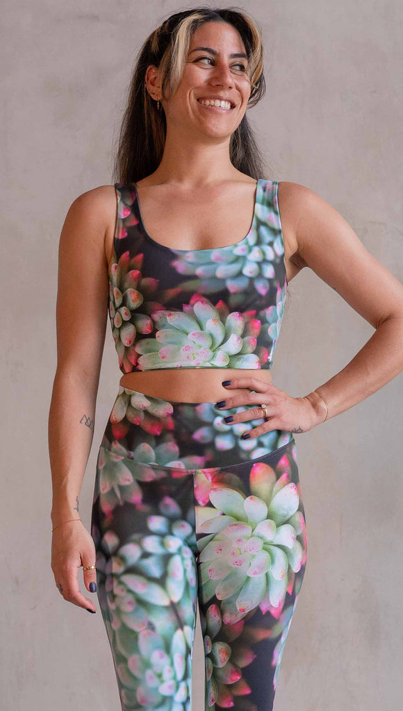 Model wearing WERKSHOP Mojave Sunset Reversible Top. One side is all green and the other side is green with bright pops of hot pink. Both sides are printed with photo-real succulents.