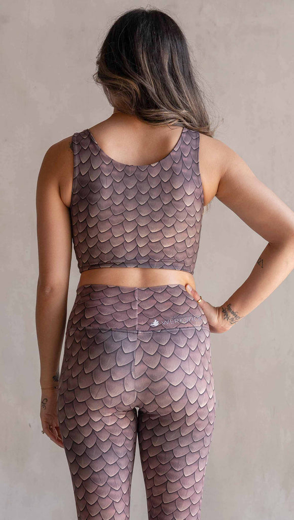 Model wearing WERKSHOP Dragon Scales Athletic top. The stop has a wide scoop neckline and is printed with mauve tone dragon scales.