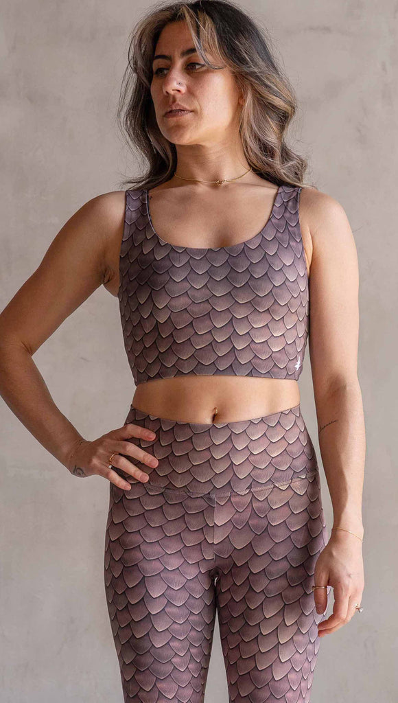 Model wearing WERKSHOP Dragon Scales Athletic top. The stop has a wide scoop neckline and is printed with mauve tone dragon scales.