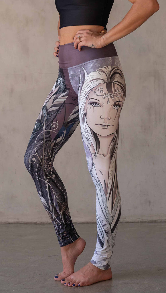 Model wearing WERKSHOP Elf + Sorceress Mashup leggings. The leggings are printed with original artwork by Chriztina Marie. One leg features a dark forest elf wearing a fur trimmed cloak. The other leg features a winter sorceress holding an orb with frosted purples and lavender tones.