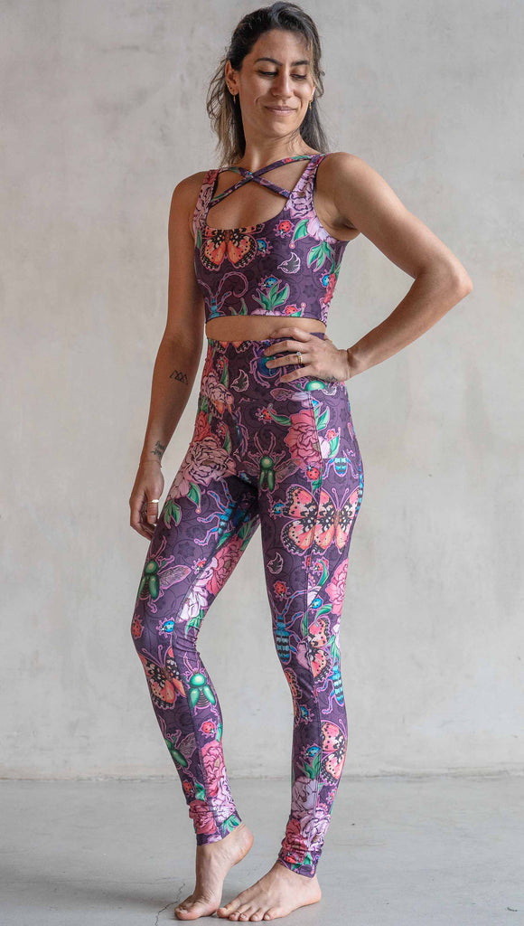 Full body front view of model wearing WERKSHOP Enchanted Garden EnviSoft Leggings with Pockets. The fabric is printed with original artwork by our Female Founder, Chriztina Marie. The artwork printed not the fabric features Butterflies, Beetles and Peonies over a warm fuchsia with bright bold pops of color on each beetle and Butterfly.