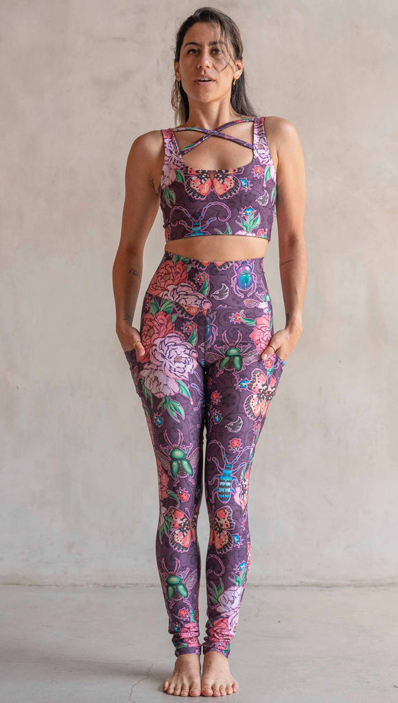 Full body front view of model wearing WERKSHOP Enchanted Garden EnviSoft Leggings with Pockets. The fabric is printed with original artwork by our Female Founder, Chriztina Marie. The artwork printed not the fabric features Butterflies, Beetles and Peonies over a warm fuchsia with bright bold pops of color on each beetle and Butterfly.