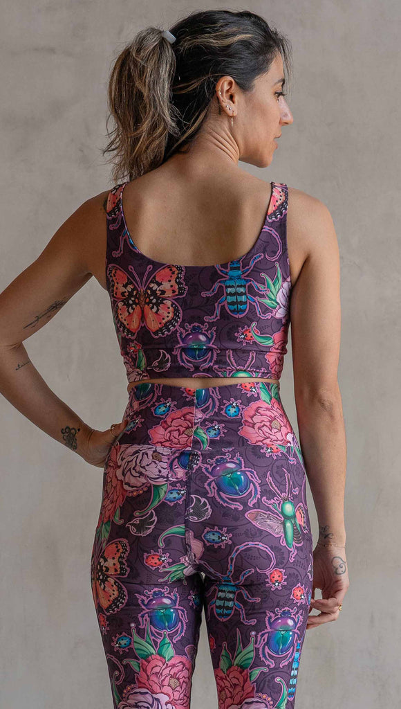 Back view of model wearing WERKSHOP Starlings and Enchanted Garden 4-Way reversible top. The fabric is printed with original artwork by Chriztina Marie. One side features European Starlings perched on a branch near a crescent moon and fireflies. The colors are warm purples with pops of pink, gold and green. The other side features Butterflies, Beetles and Peonies over a warm fuchsia with bright bold pops of color on each beetle and Butterly.