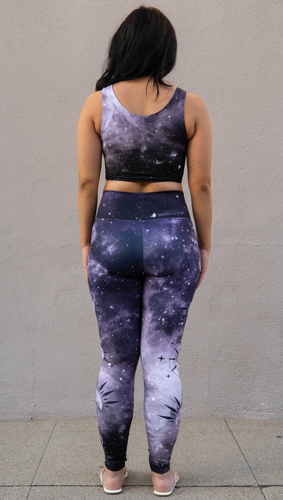 Model wearing "Feyre's Tattoo" Leggings with a dark purplish-blue to black ombre celestial background and moon phases on each leg. Officially licensed for A Court of Thorns and Roses by Sarah J Maas. It has the phrase, "Hello, Feyre Darling" on the waistband.