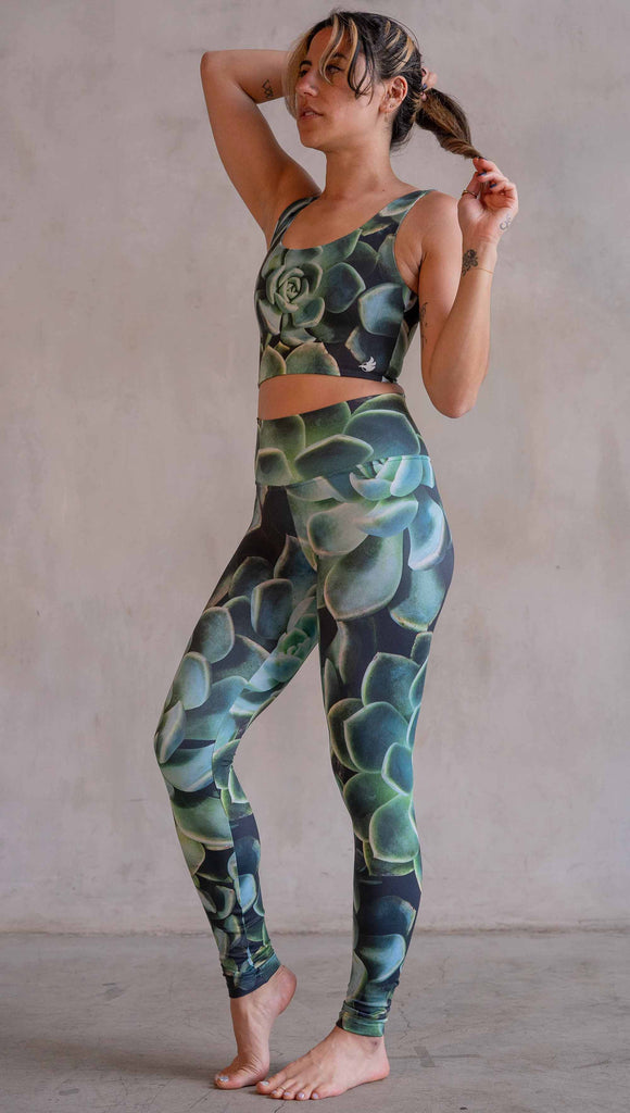 Model wearing WERKSHOP Green Envy Athleisure Leggings. The leggings are printed with a photo-real macro green succulent clusters.