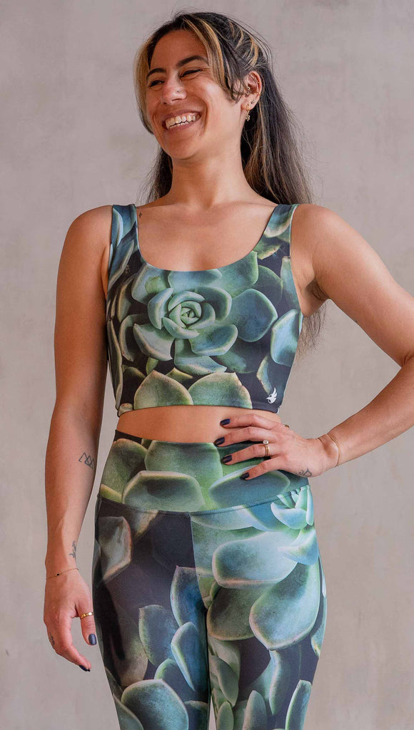 Model wearing WERKSHOP Mojave Sunset Reversible Top. One side is all green and the other side is green with bright pops of hot pink. Both sides are printed with photo-real succulents.