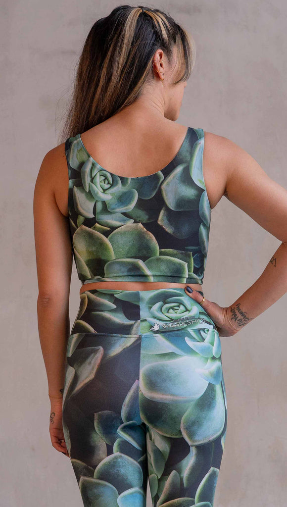 Model wearing WERKSHOP Mojave Sunset Reversible Top. One side is all green and the other side is green with bright pops of hot pink. Both sides are printed with photo-real succulents.