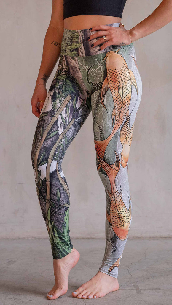  Model wearing WERKSHOP Koi Fish and Giant Panda Mashup Leggings. The wearer's right leg has an illustration of a panda eating bamboo with a gorgeous background of mountains. The wearers right leg has koi fishies swimming over an abstract taupe and forest green background.