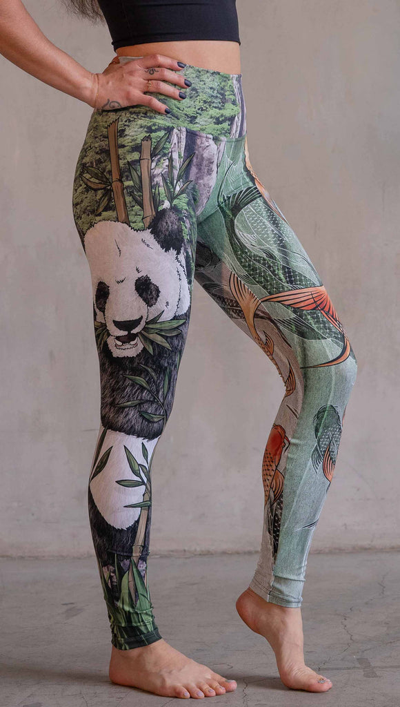  Model wearing WERKSHOP Koi Fish and Giant Panda Mashup Leggings. The wearer's right leg has an illustration of a panda eating bamboo with a gorgeous background of mountains. The wearers right leg has koi fishies swimming over an abstract taupe and forest green background.