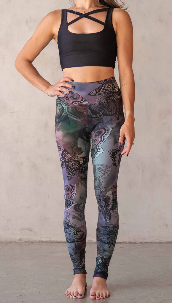 Front view of model wearing WERKSHOP Moths athlisure leggings. The artwork on the leggings is of hand drawn moths with muted pops of mauve and peach over an edgy "oil slick" inspired watercolor background.