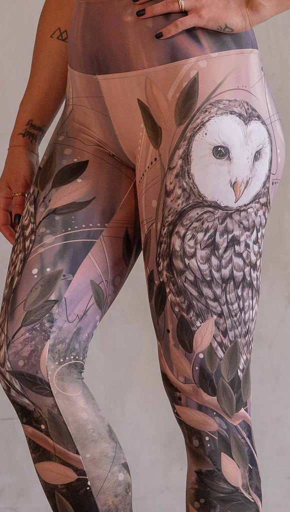 Model wearing WERKSHOP Owls Athleisure Leggings. The leggings are printed with a whimsical barn owl on the thigh surrounded by swirls and leaves on a mauve and cream toned background.