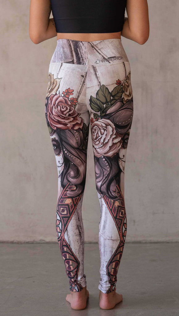 Girl wearing WERKSHOP "Remix" SugarSkull Athelisure leggings. The artwork printed on the leggings features a girl wearing Dia De Los Muertos makeup with a crown of roses and a beaded necklace with a romantic color woodgrain background.