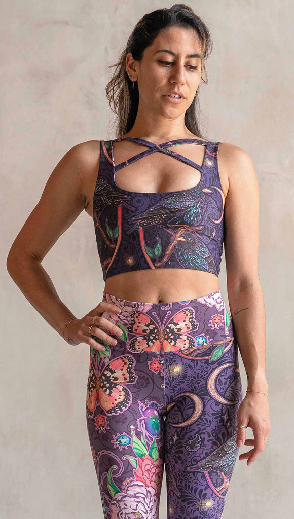 Front view of model wearing WERKSHOP Starlings and Enchanted Garden 4-Way reversible top. The fabric is printed with original artwork by Chriztina Marie. One side features European Starlings perched on a branch near a crescent moon and fireflies. The colors are warm purples with pops of pink, gold and green. The other side features Butterflies, Beetles and Peonies over a warm fuchsia with bright bold pops of color on each beetle and Butterly.