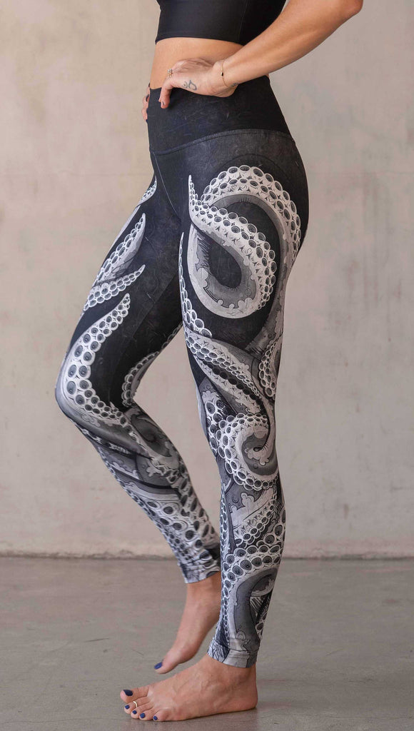 Model wearing WERKSHOP Tentacles Athleisure Leggings. The artwork on the leggings features hand drawn tentacles wrapping up and around each leg in colors of black and white with distressed texture.