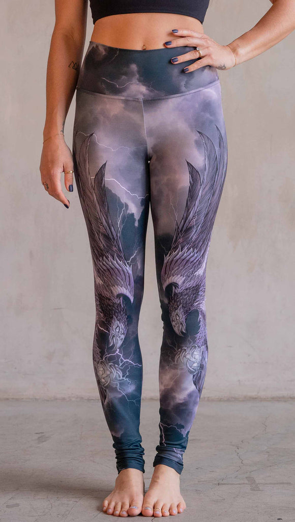 Model wearing WERKSHOP Thunderbird Athleisure Leggings. The artwork printed on the leggings features a thunderbird flying through a stormy sky with lightening. The leggings feature a closed colour pallete with all shades of purple.