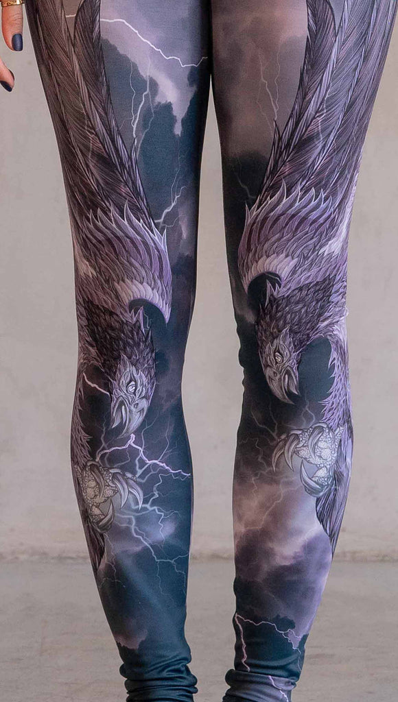 Model wearing WERKSHOP Thunderbird Athleisure Leggings. The artwork printed on the leggings features a thunderbird flying through a stormy sky with lightening. The leggings feature a closed colour pallete with all shades of purple.