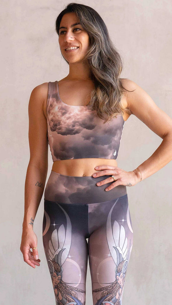 Side view of model wearing WERKSHOP Athena and Valkyrie reversible top. This top is two way reversible and each side matches either our Athena or Valkyrie leggings. The Athena side of the top features a cloudy blue sky with rays of sunlight. The Valkyrie side features an ominous taupe and warm gray stormy sky with lightening bolts