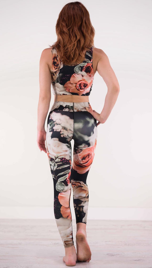 Back view of model wearing black triathlon leggings with pink and white roses and leafy greens throughout