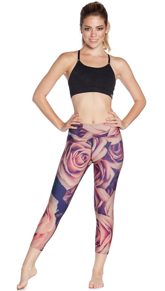 front view of model wearing printed capri leggings with all-over rose design motif and sports top