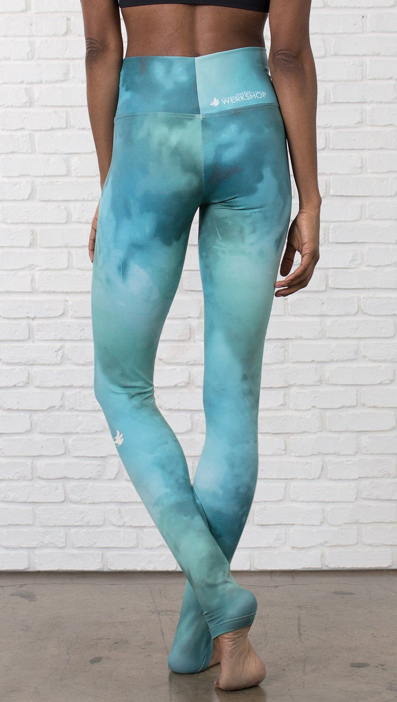 closeup back view of model wearing water / ocean themed printed full length leggings with black sports top