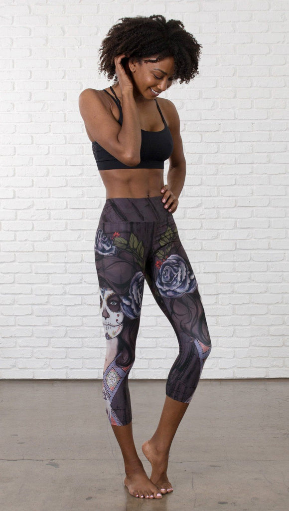 front view of model wearing sugar skull themed printed capri leggings