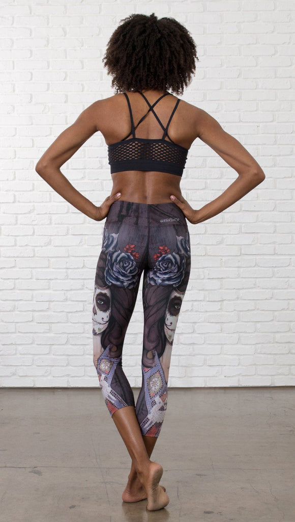 back view of model wearing sugar skull themed printed capri leggings