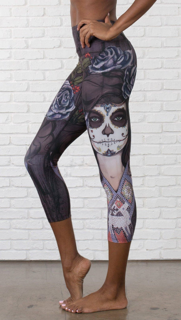 close up left side view of model wearing sugar skull themed printed capri leggings