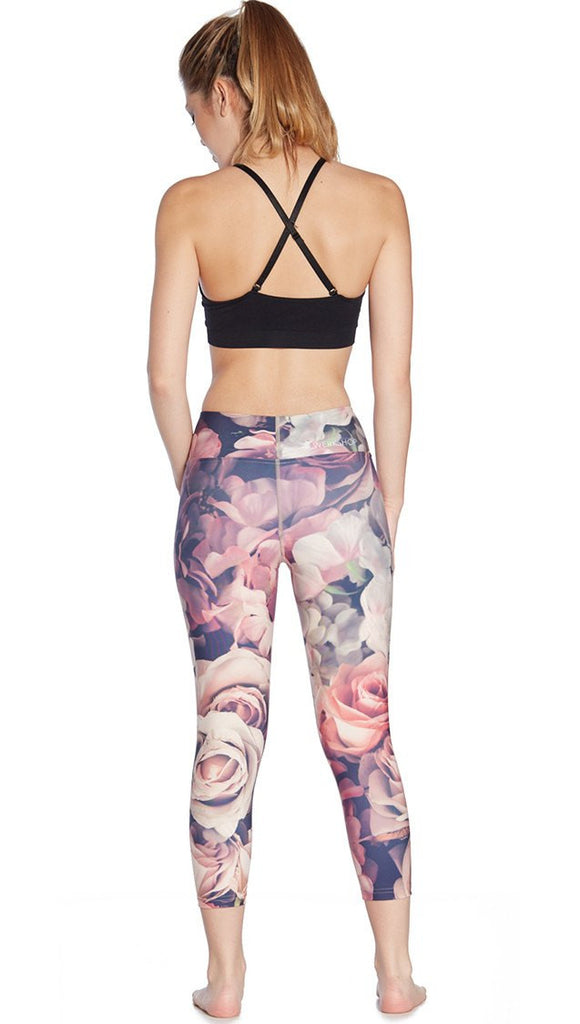 back view of model wearing pink floral printed capri leggings