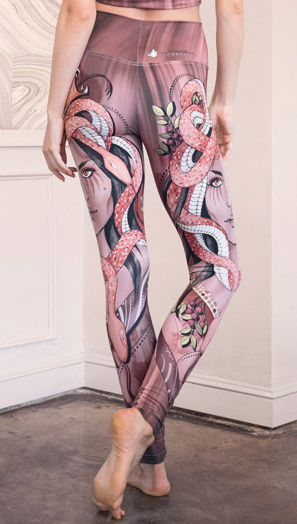 Zoomed in back view of the model wearing full length athleisure leggings with a mauve color medusa head and red, white, and black snakes