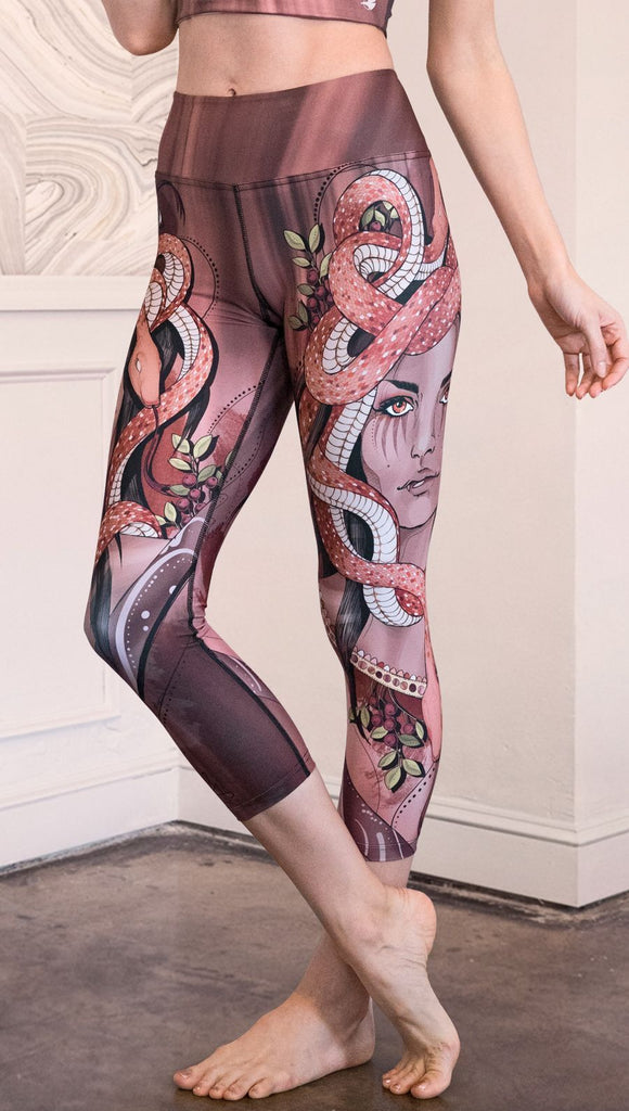 Model wearing capri leggings with a mauve color medusa head and red, white, and black snakes