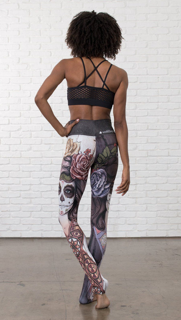 back view of model wearing mashup Sugar Skull and Dia De Los Muertos themed printed full length leggings