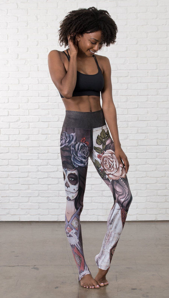 front view of model wearing mashup Sugar Skull and Dia De Los Muertos themed printed full length leggings