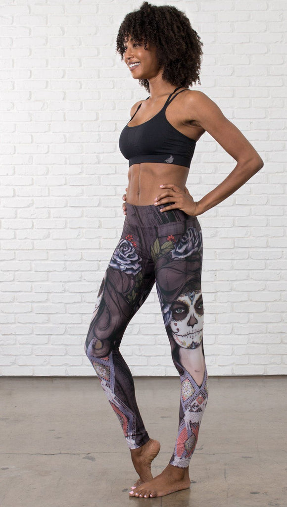 slightly turned front view of model wearing sugar skull themed printed full length leggings