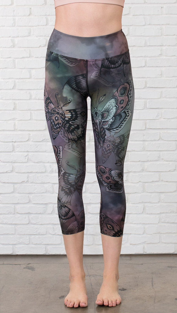 closeup front view of model wearing capri printed leggings with gothic moths, gargoyles, skulls, ravens design